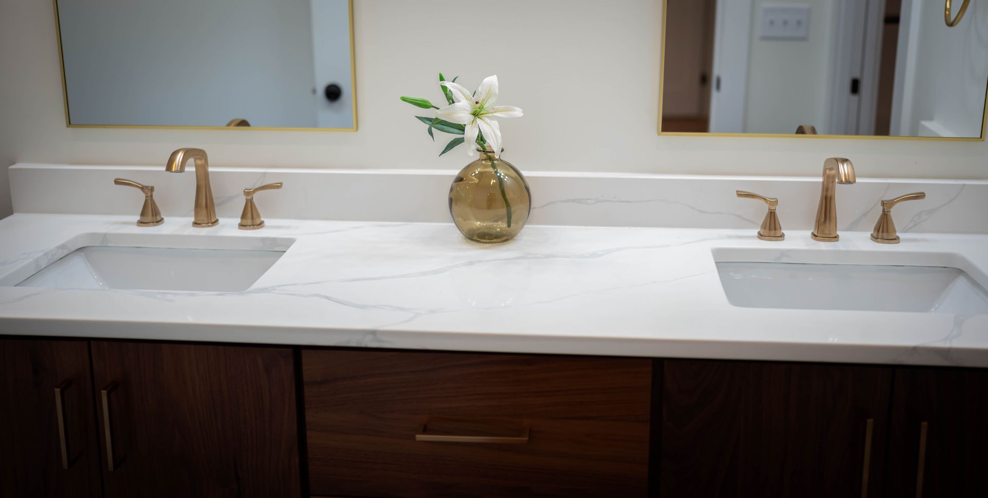 A bathroom with two sinks and a vase of flowers on the counter.