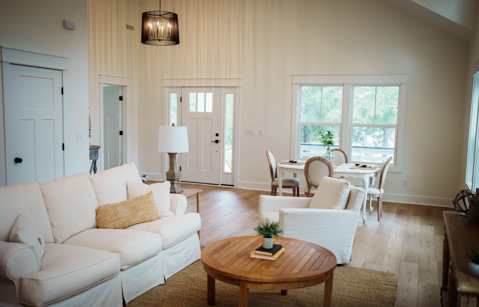 A living room with white furniture and a wooden table