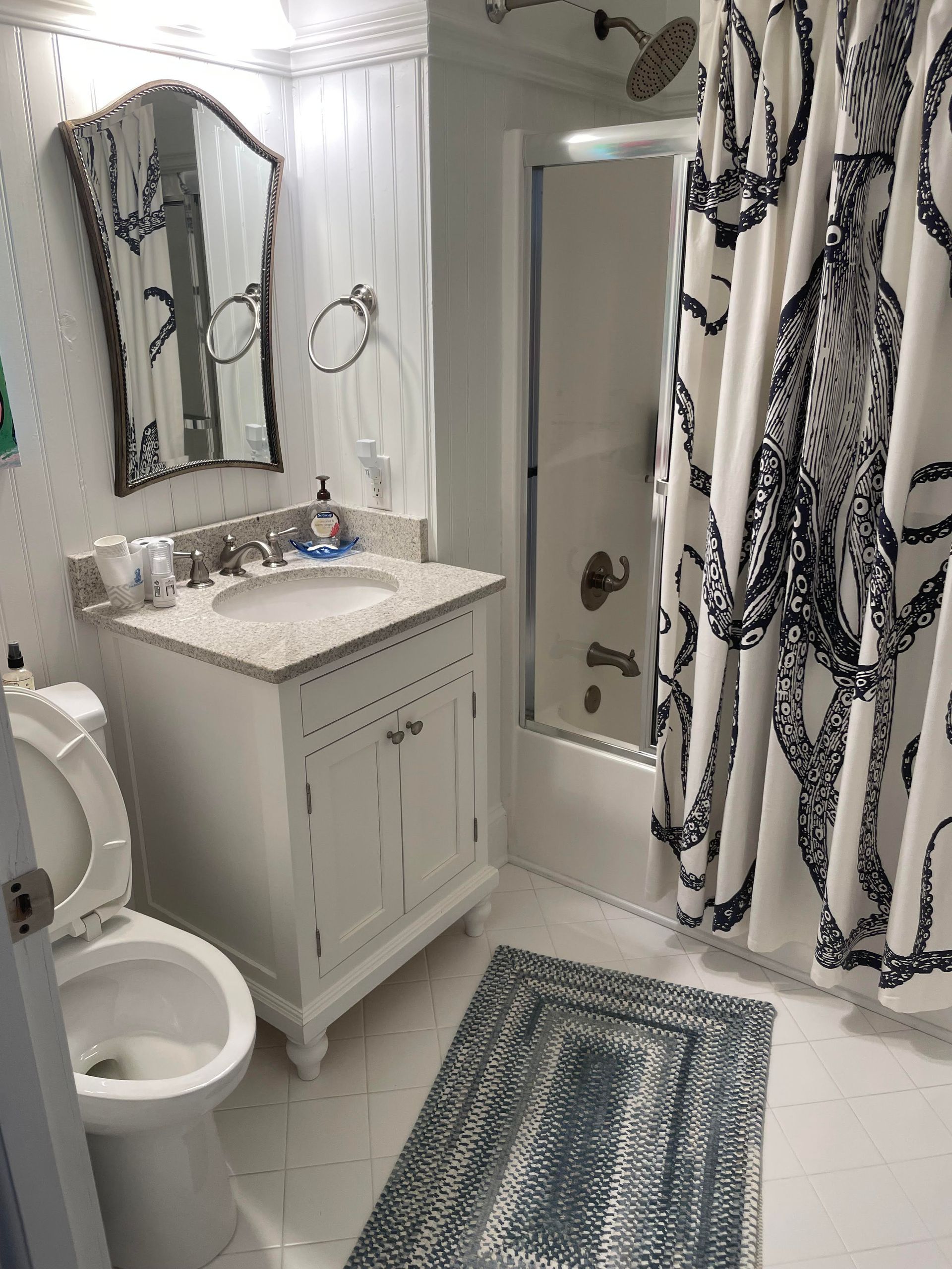 A bathroom with a toilet , sink , mirror and shower curtain