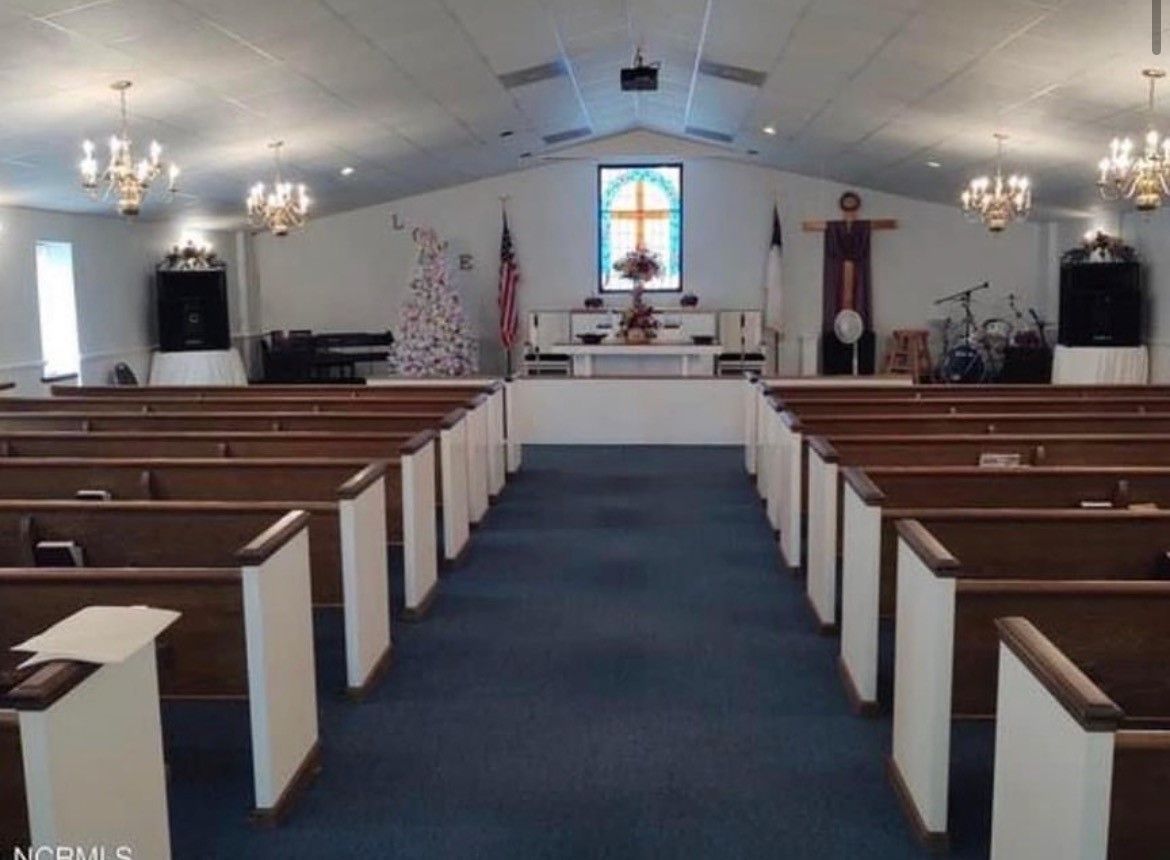 A church with rows of wooden pews and a stained glass window