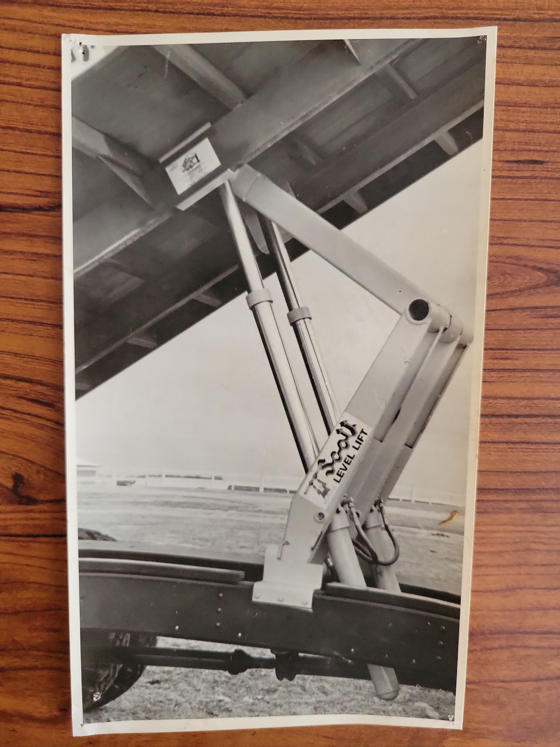 A black and white photo of a hydraulic lift on a wooden table