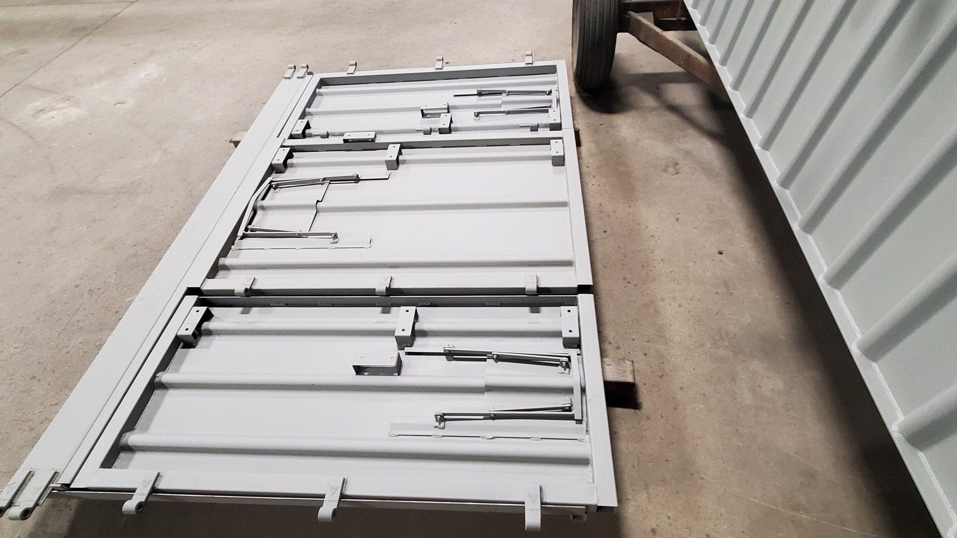 A piece of metal is laying on the ground next to a container.