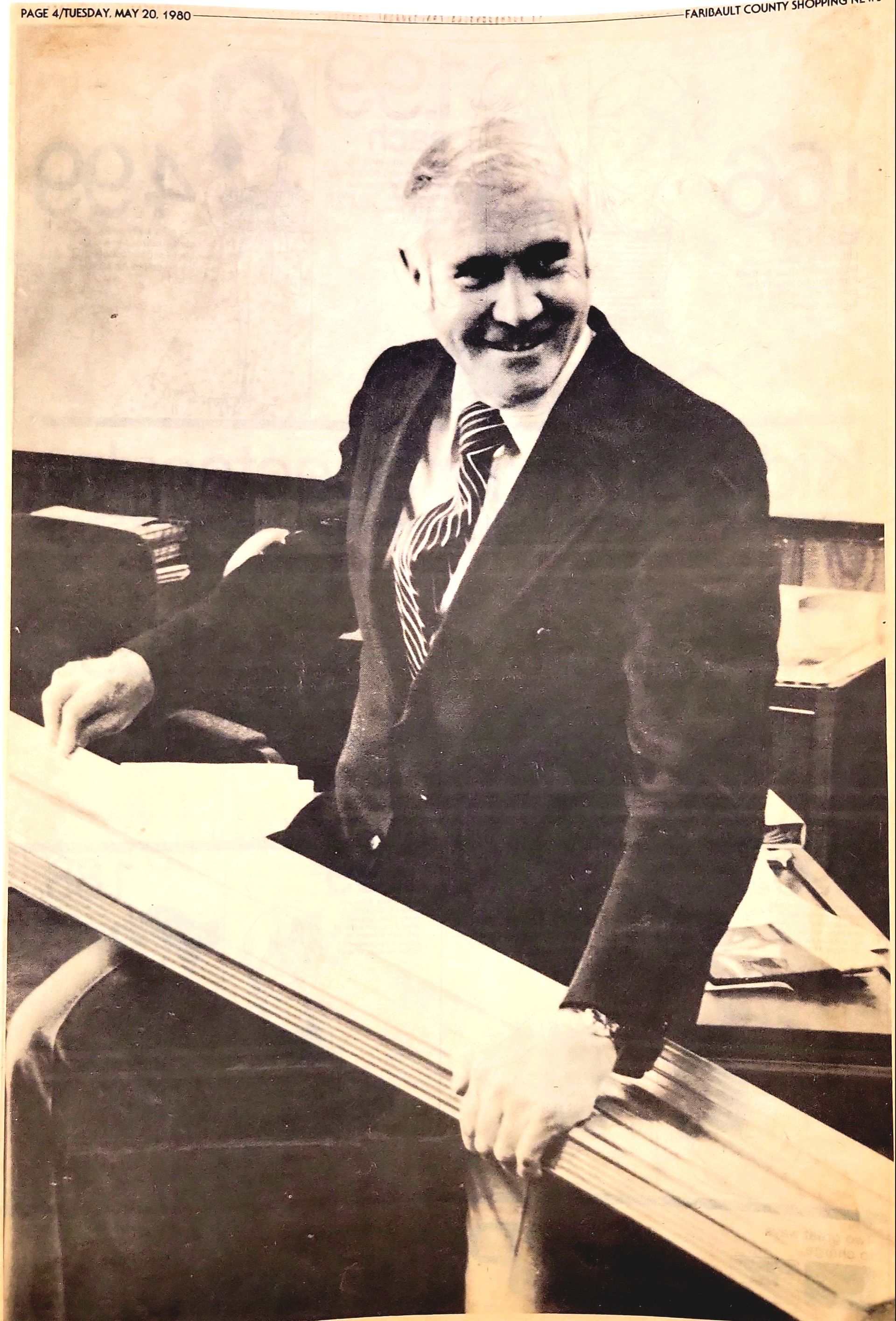 A man in a suit and tie is holding a piece of wood