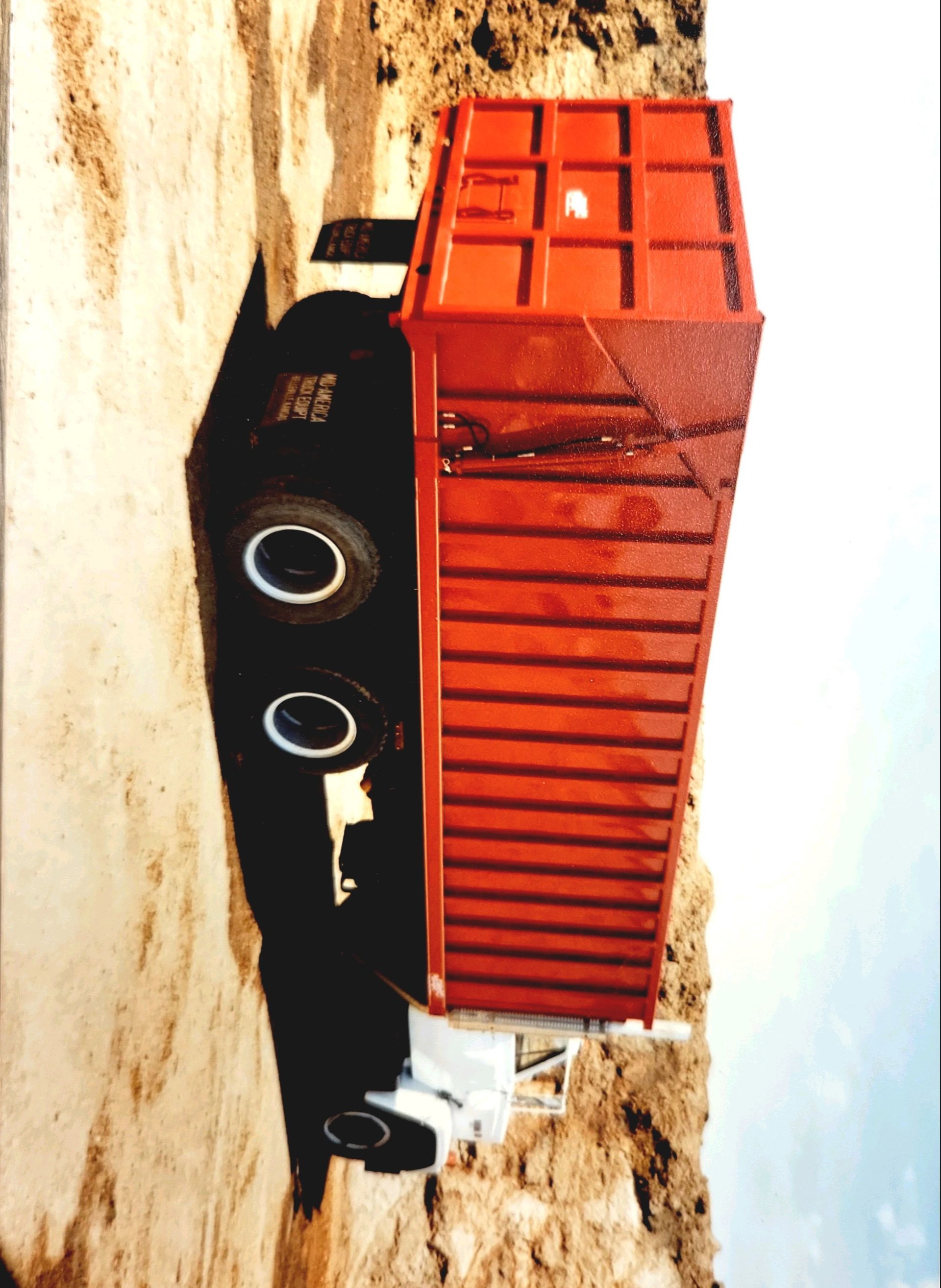 A red truck is parked on the side of a hill