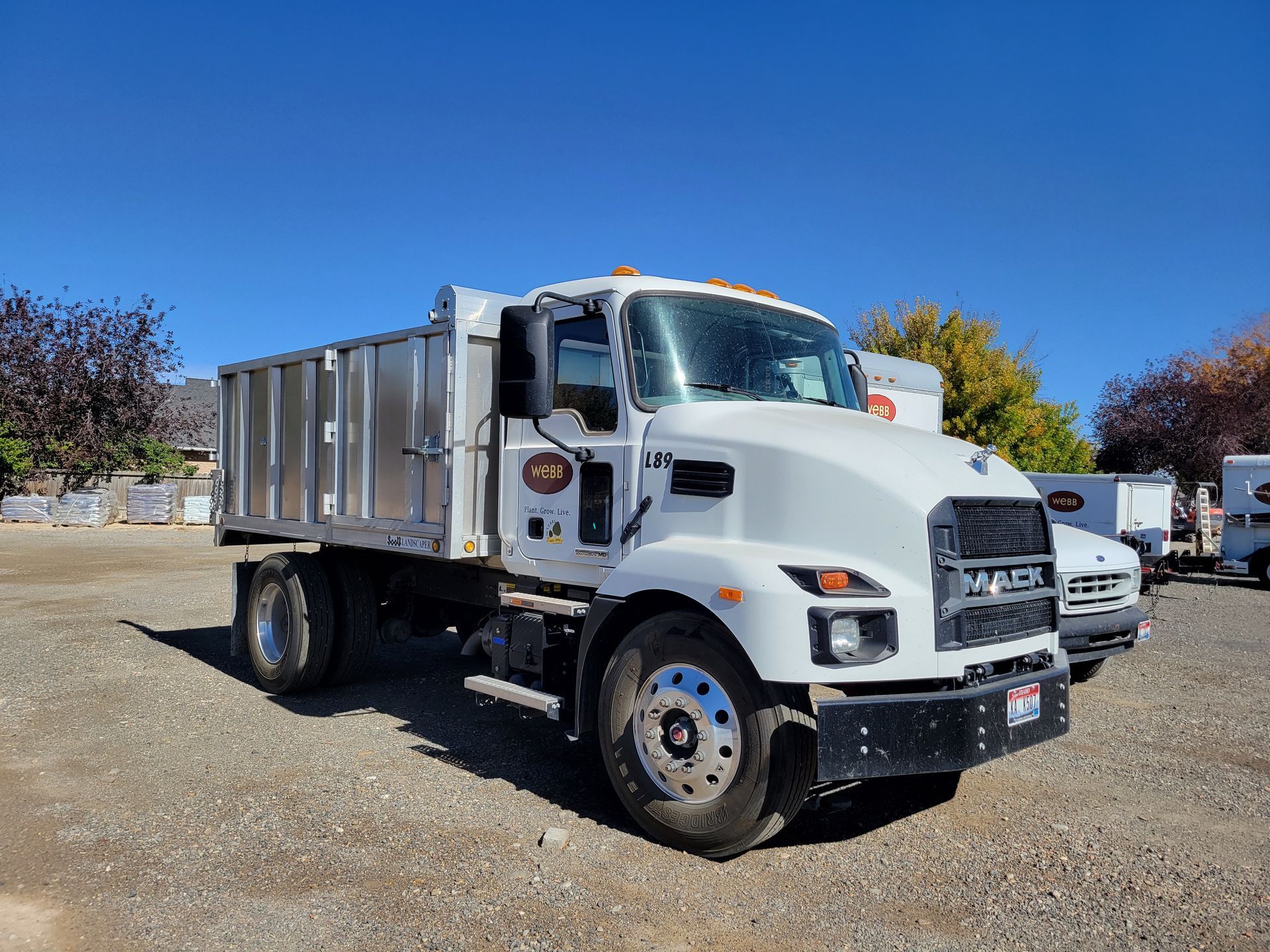 A white dump truck is parked in a gravel lot.