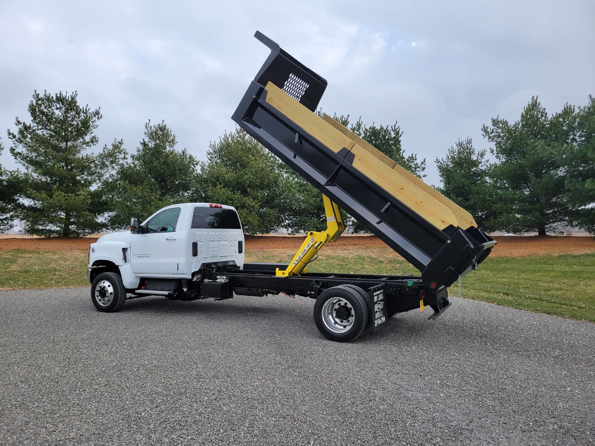 A white dump truck is parked on the side of the road.