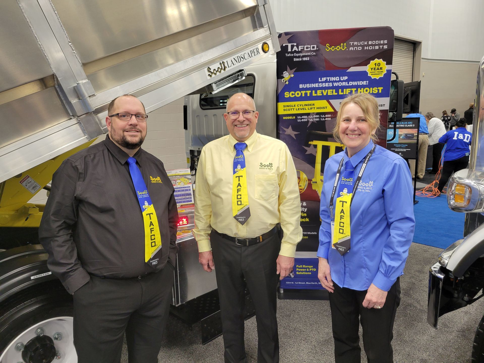 Three people are standing next to each other in front of a truck.