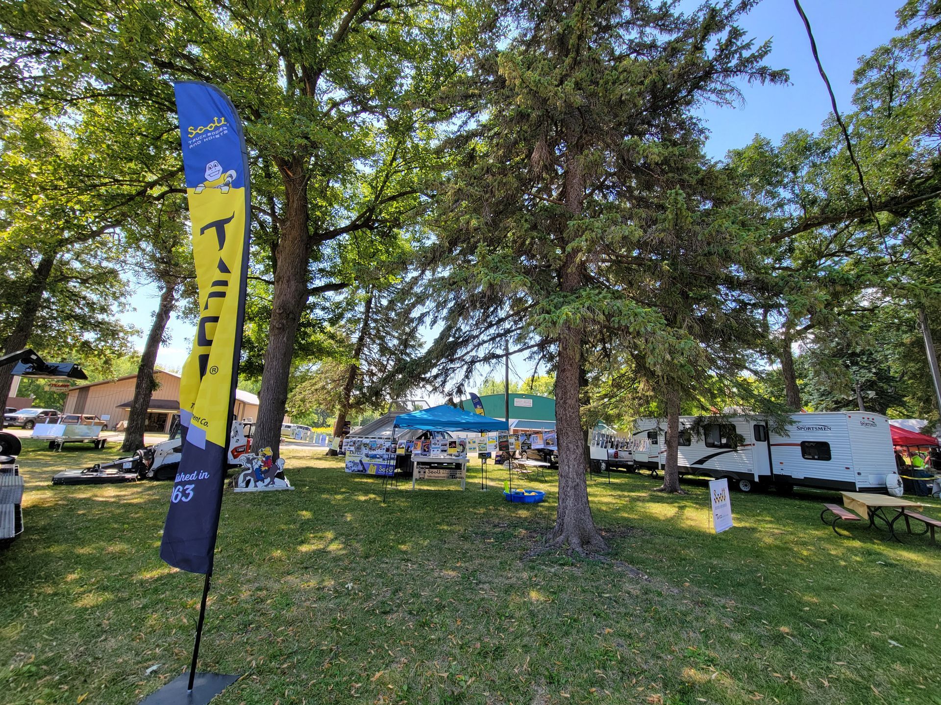 A yellow and blue flag with the letter t on it is in a park surrounded by trees.