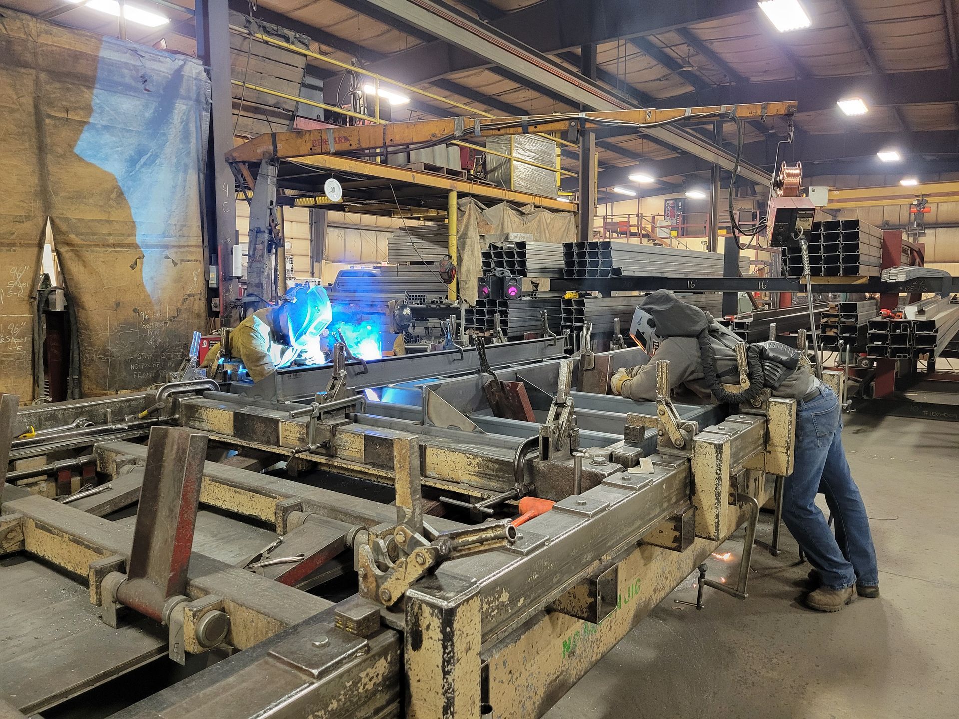 A man is welding a piece of metal in a factory.