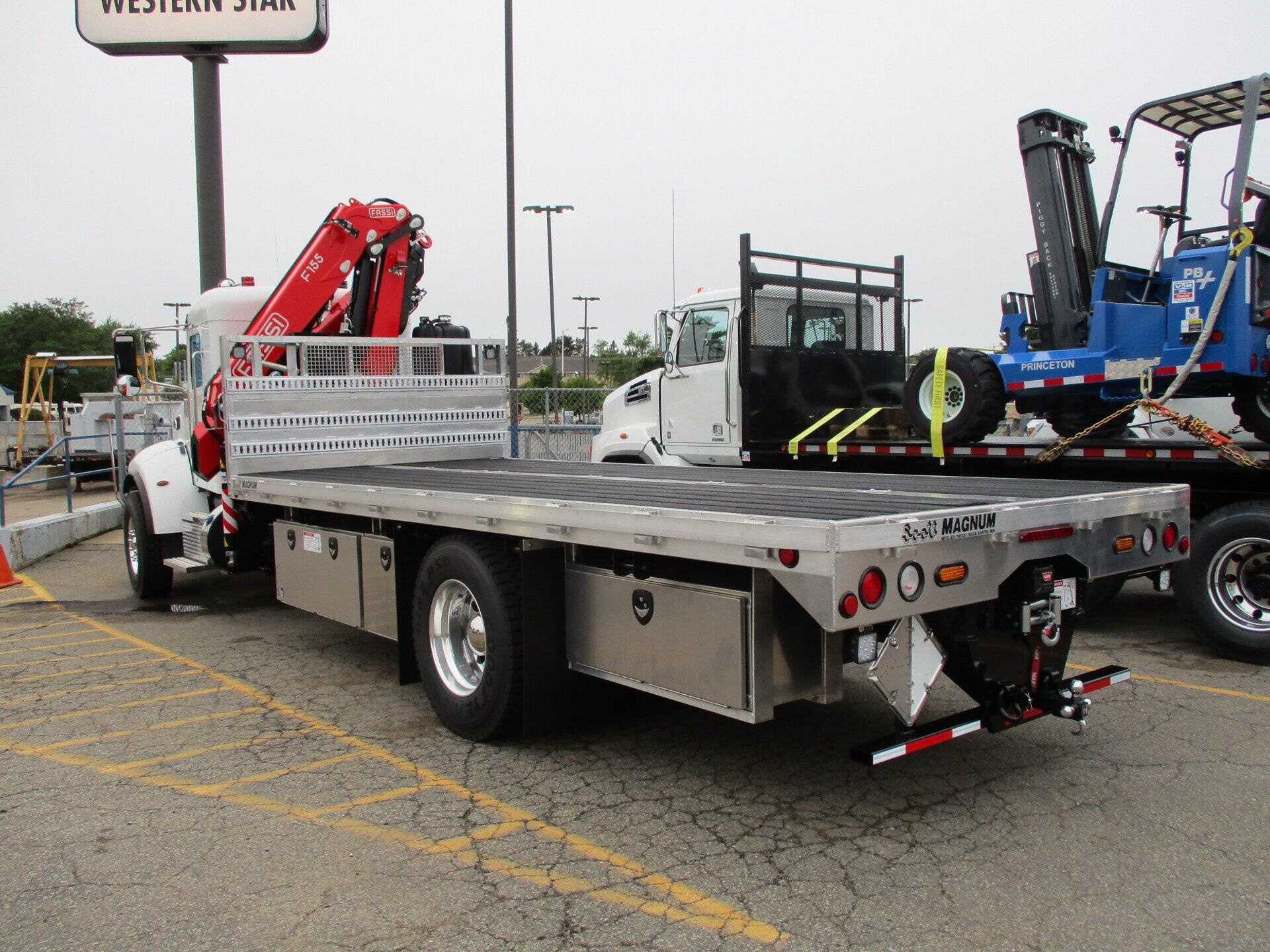 A flatbed truck with a crane on the back is parked in a parking lot