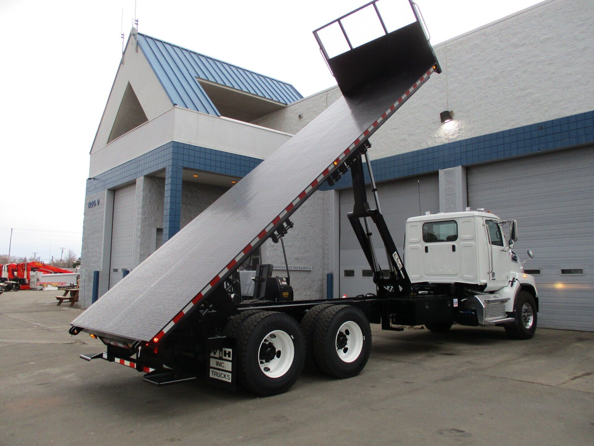 A white dump truck is parked in front of a building