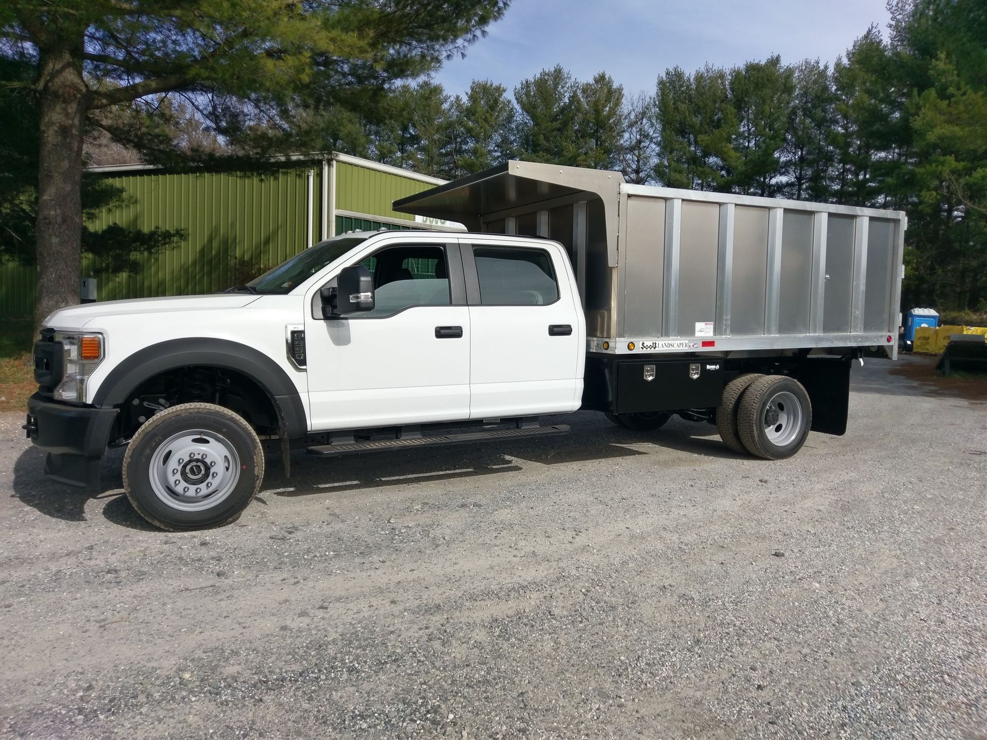 A white dump truck is parked in a gravel lot.
