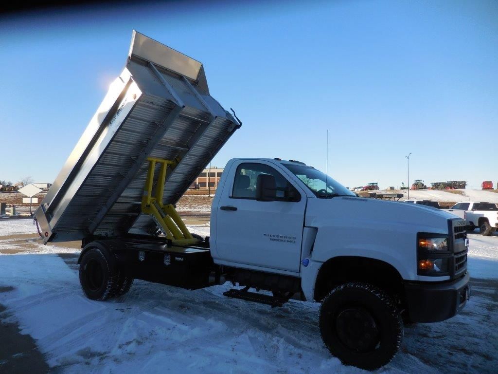 A white dump truck is parked in the snow.