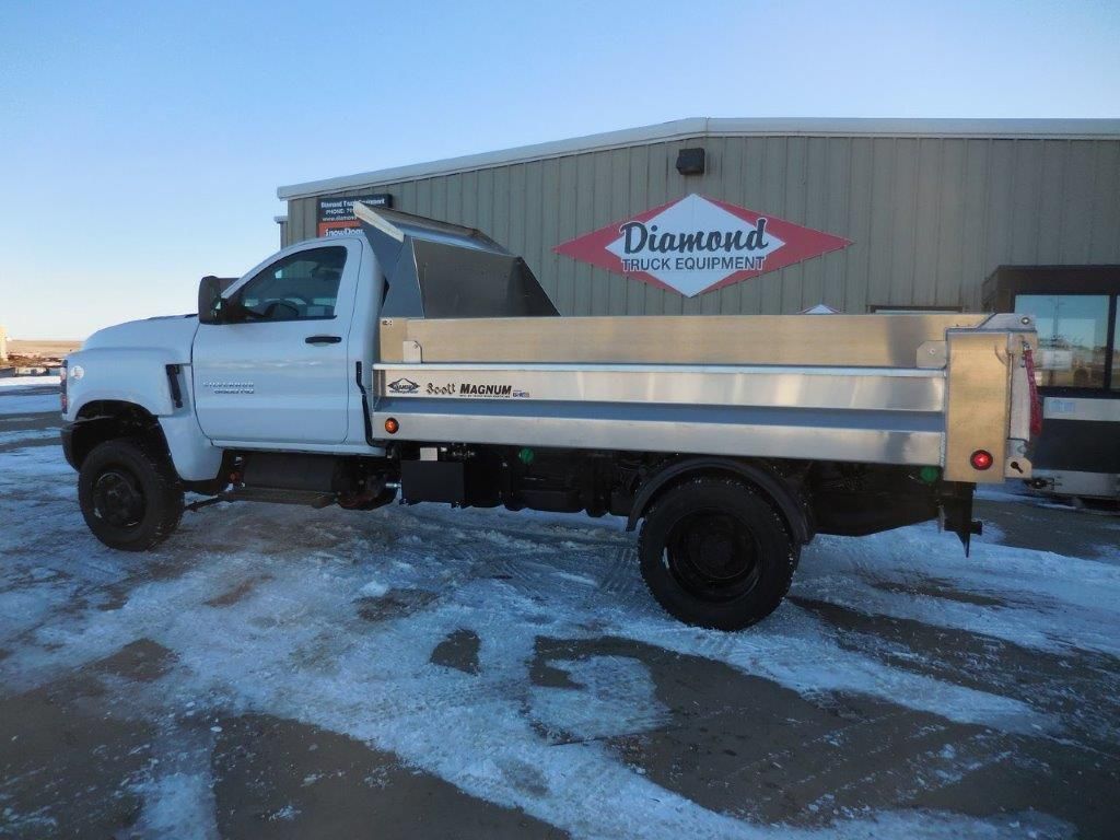A dump truck is parked in the snow in front of a building.