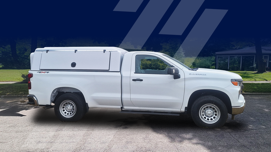 White pickup truck with a white utility bed on a paved road.