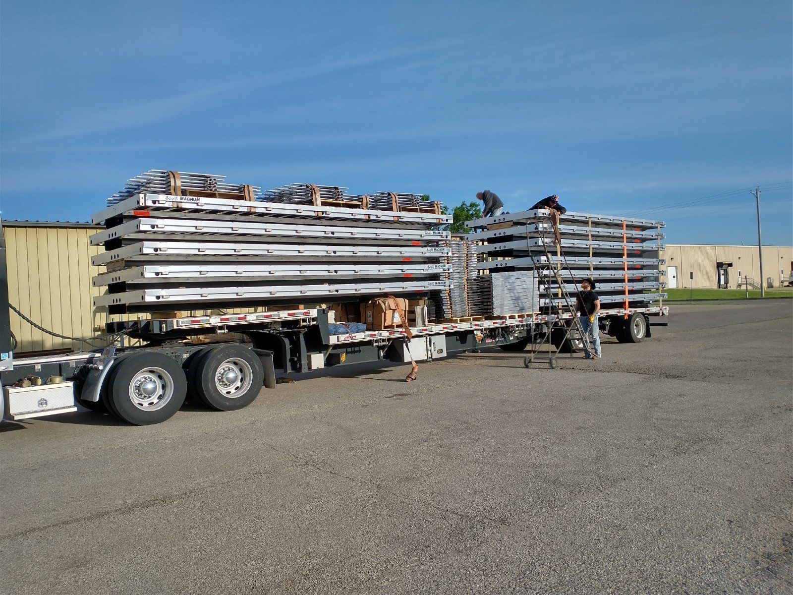 A semi truck is carrying a stack of pallets on a trailer.