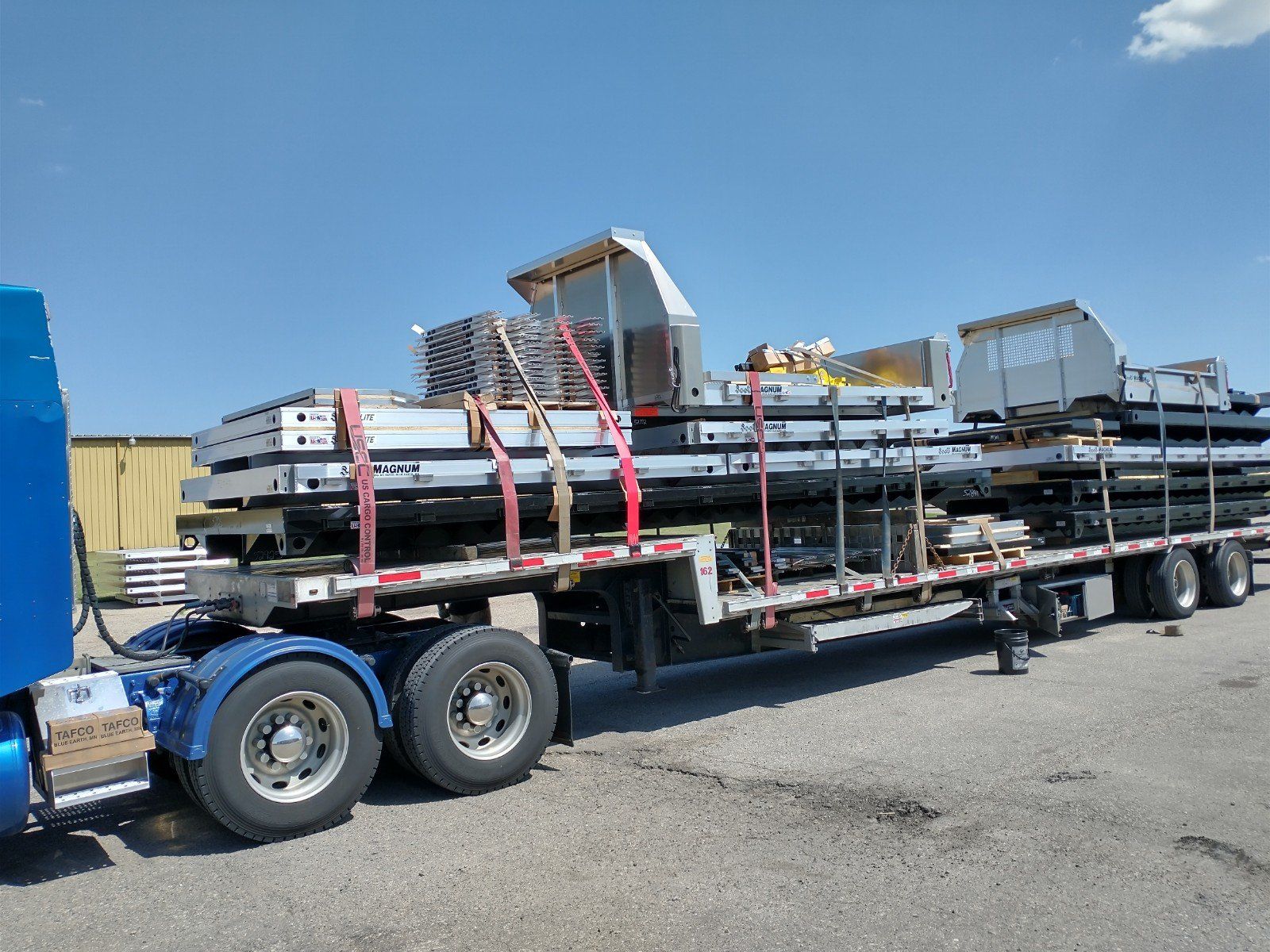 A blue semi truck is carrying a large load of metal.