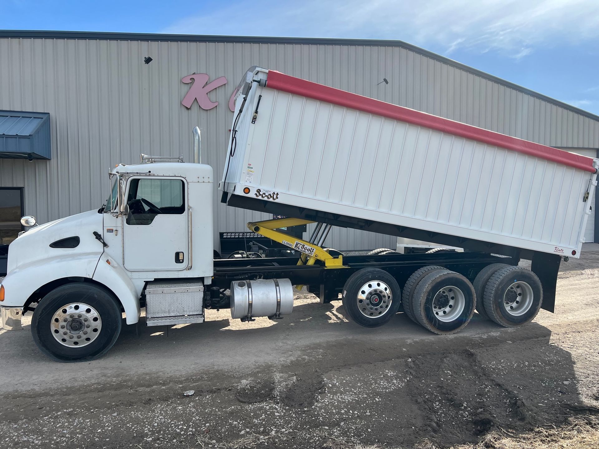 A white dump truck is parked in front of a building.