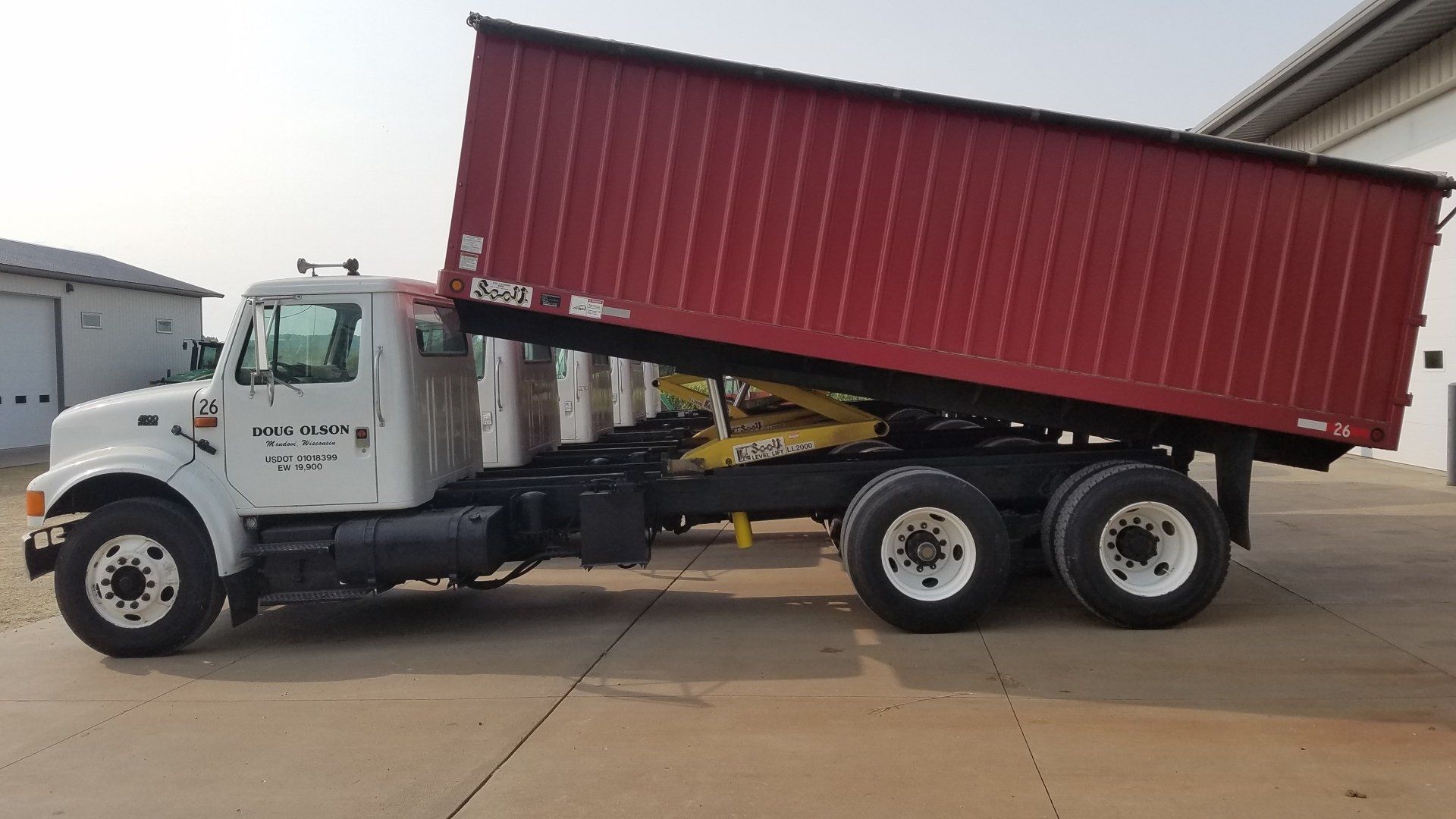 A white dump truck with a red roof is parked in a parking lot.