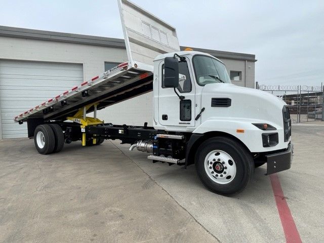A white tow truck is parked in front of a garage.