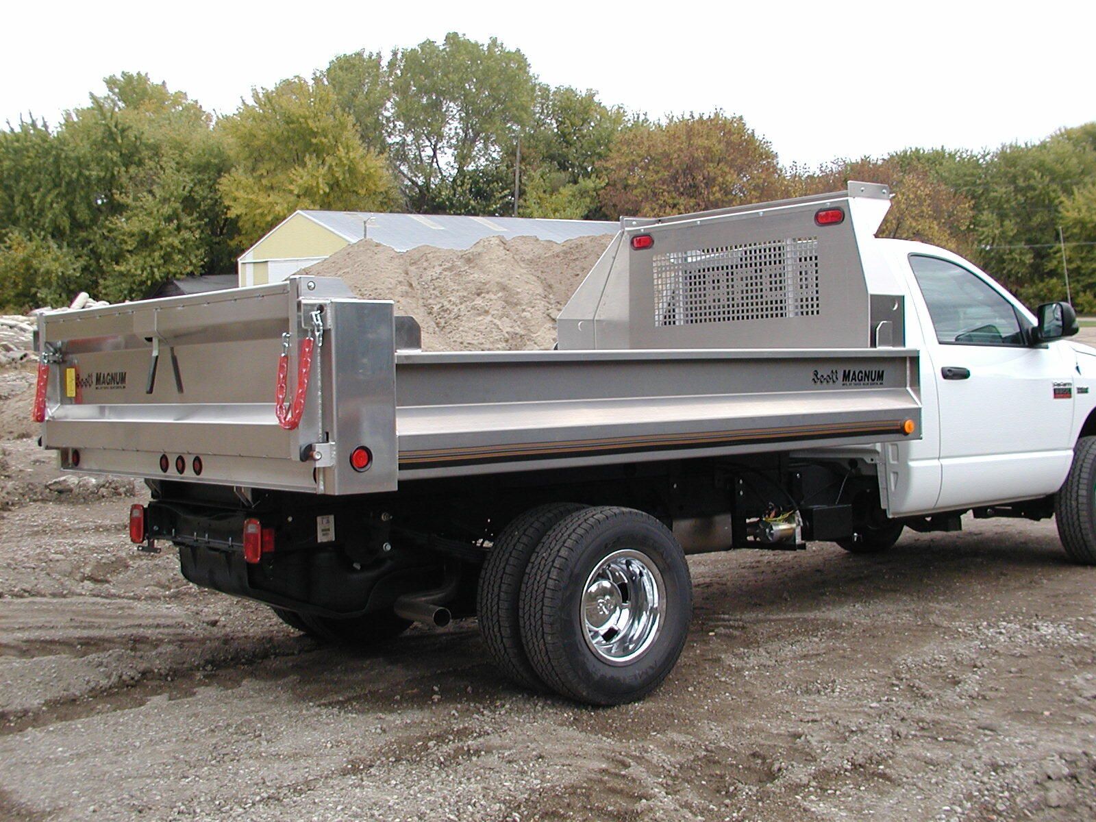 A white dump truck is parked in a dirt lot