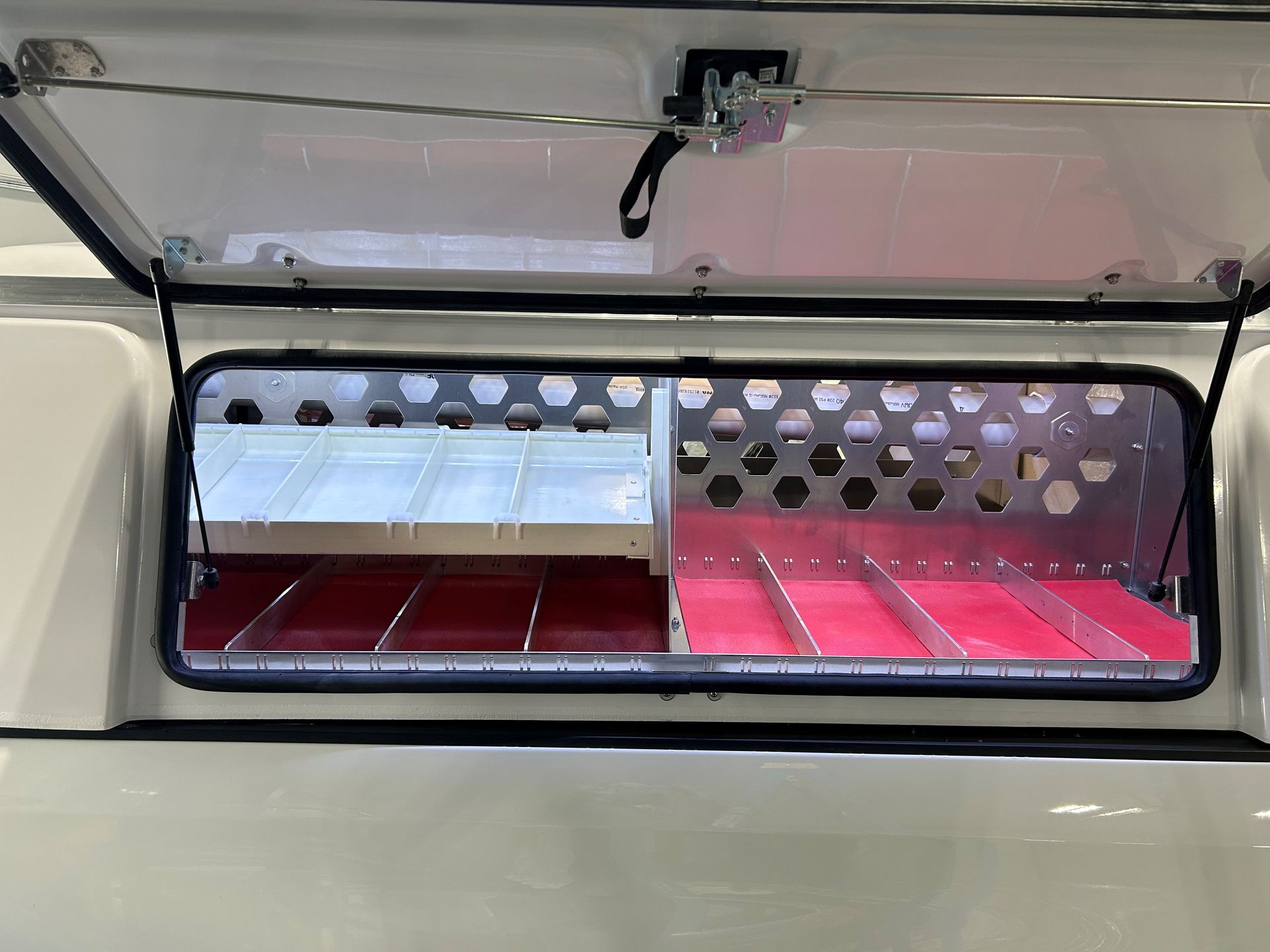 A white truck with the roof open and a red shelf in the back.