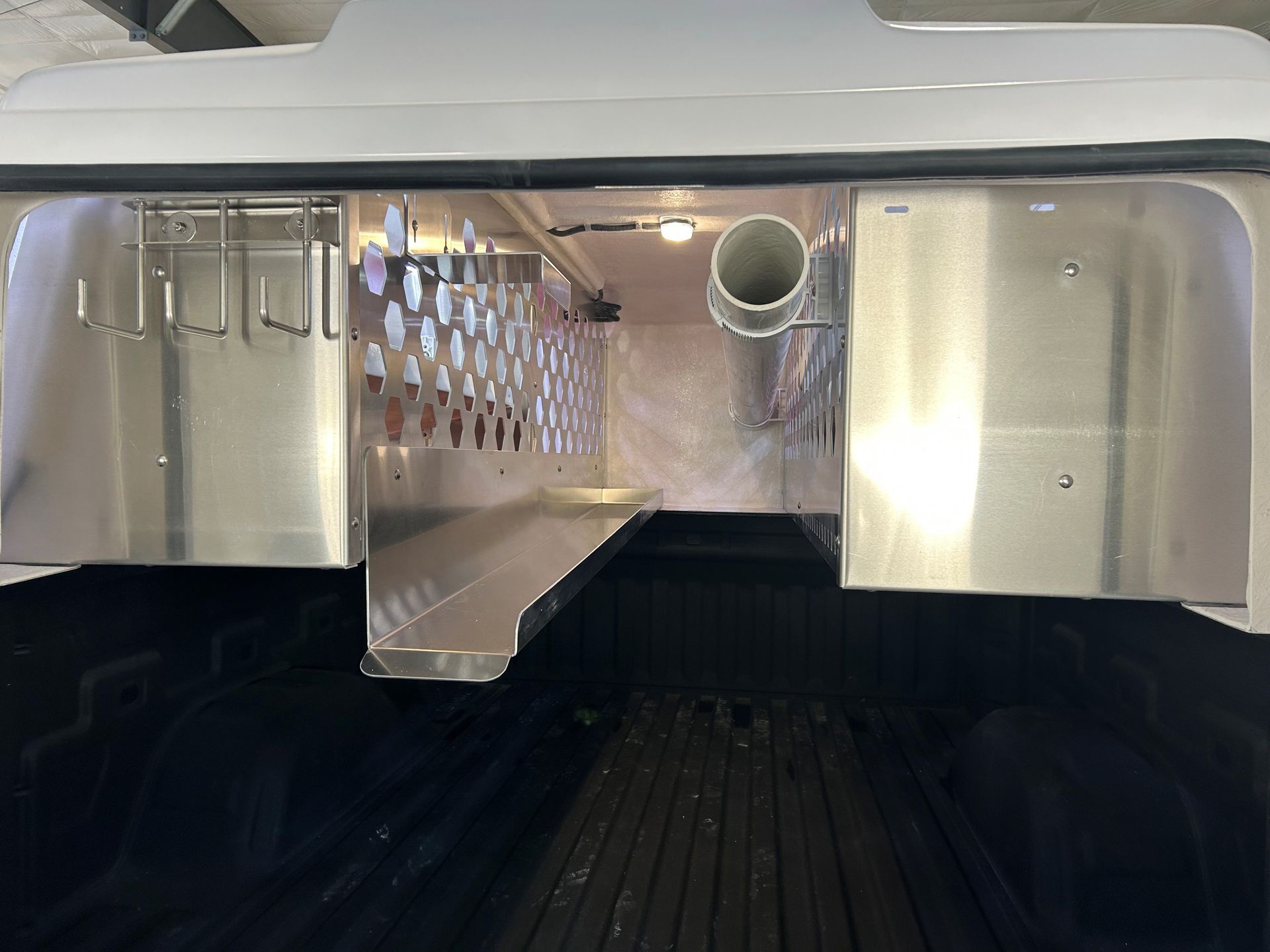 A stainless steel shelf is sitting in the back of a truck.