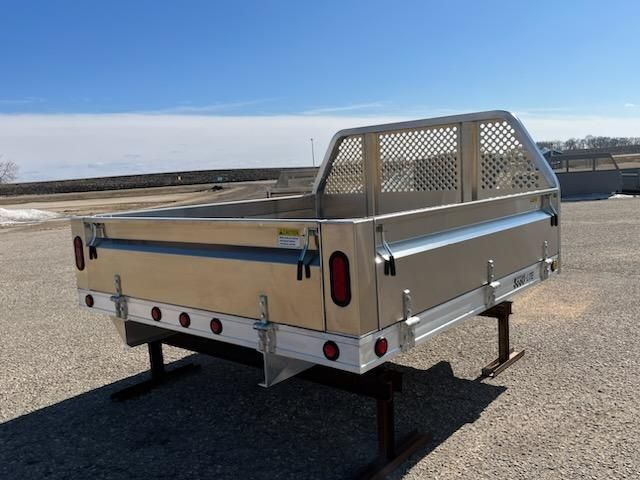 An aluminum truck bed is sitting on the ground in a parking lot.