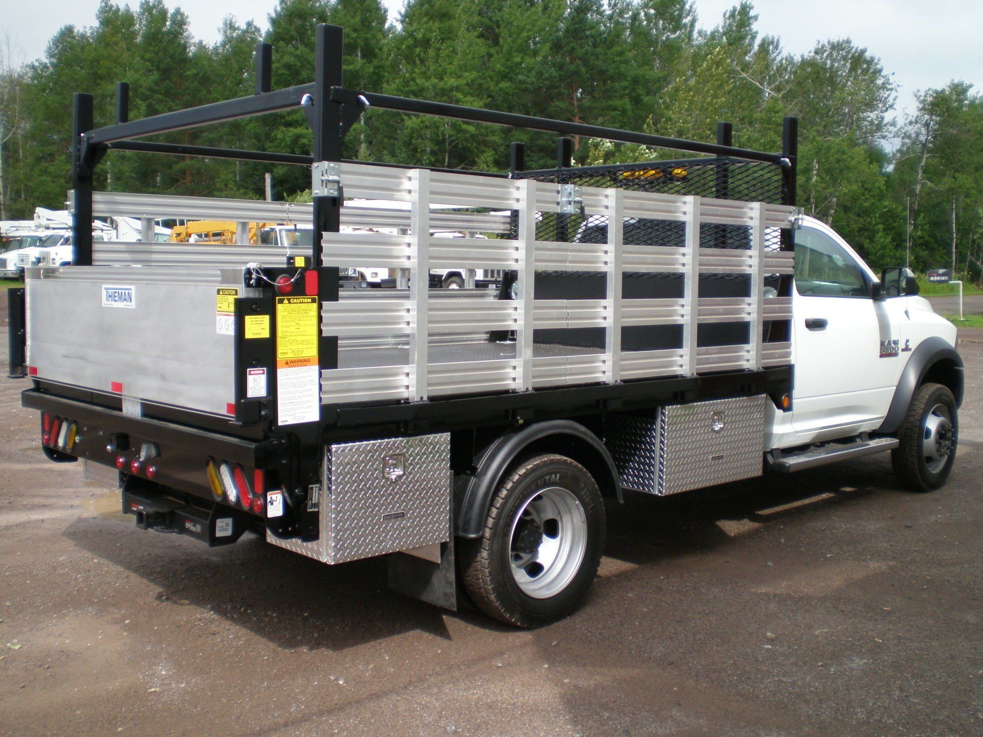 A white truck with a cage on the back is parked in a parking lot