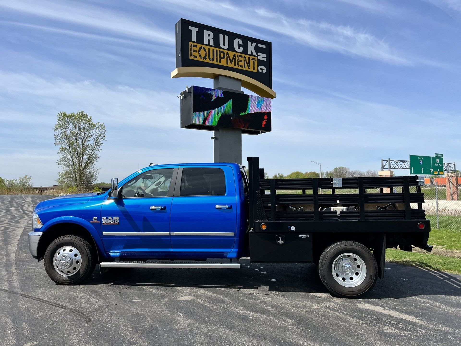A blue truck is parked in front of a truck equipment sign.