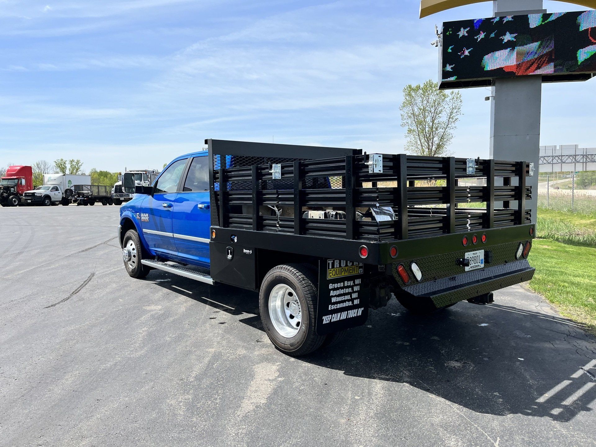 A blue truck with a wooden bed is parked in a parking lot.