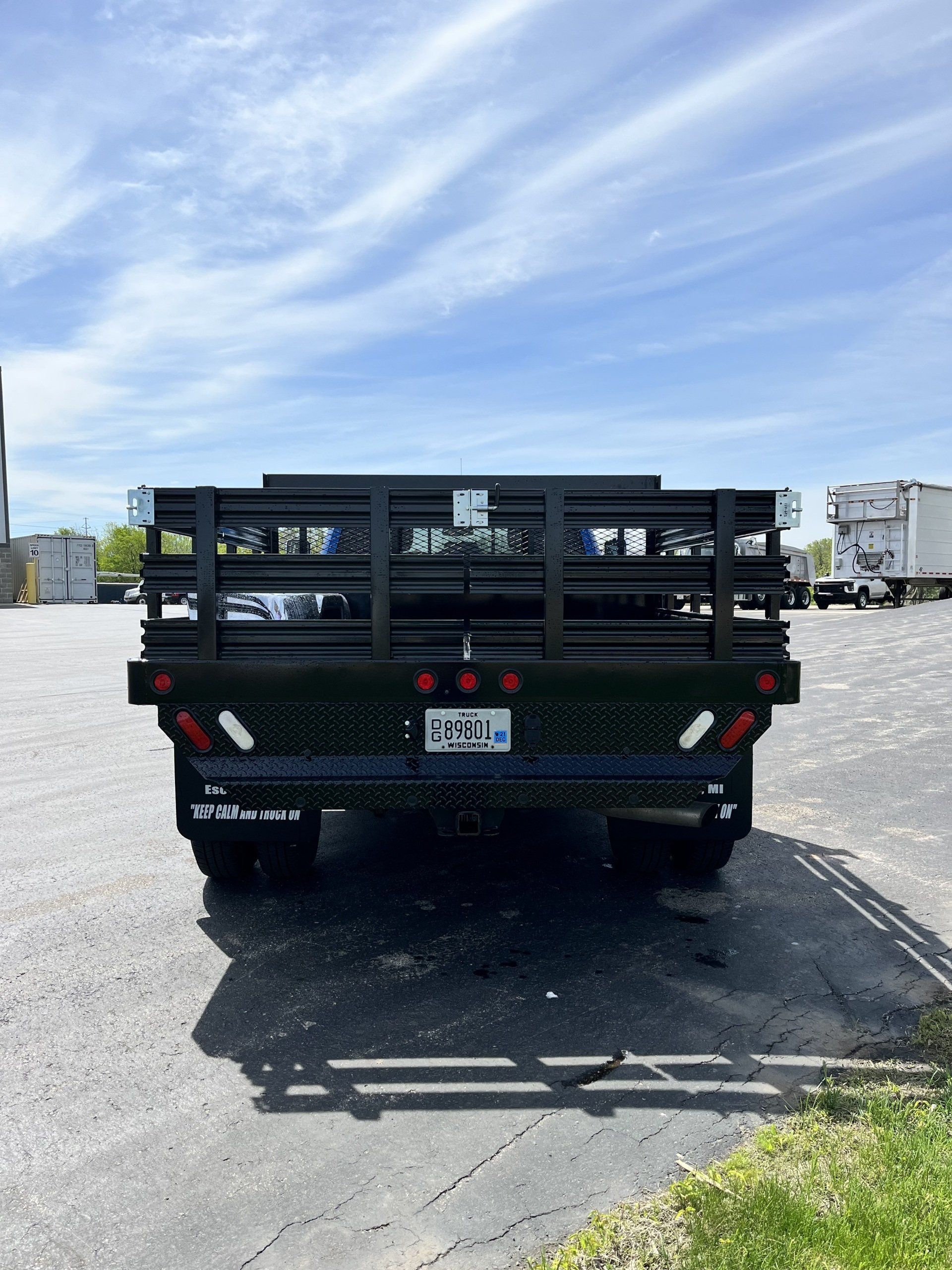 The back of a flatbed truck is parked in a parking lot.