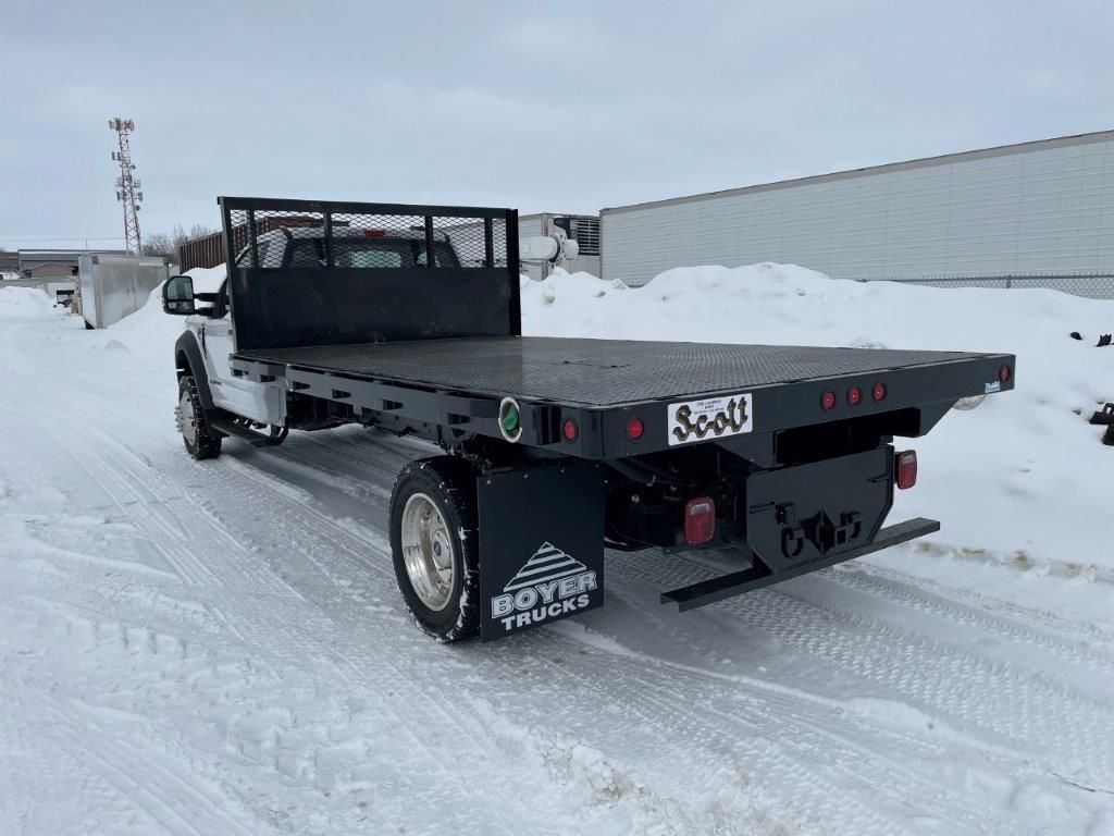 A flatbed truck is parked on a snowy road.