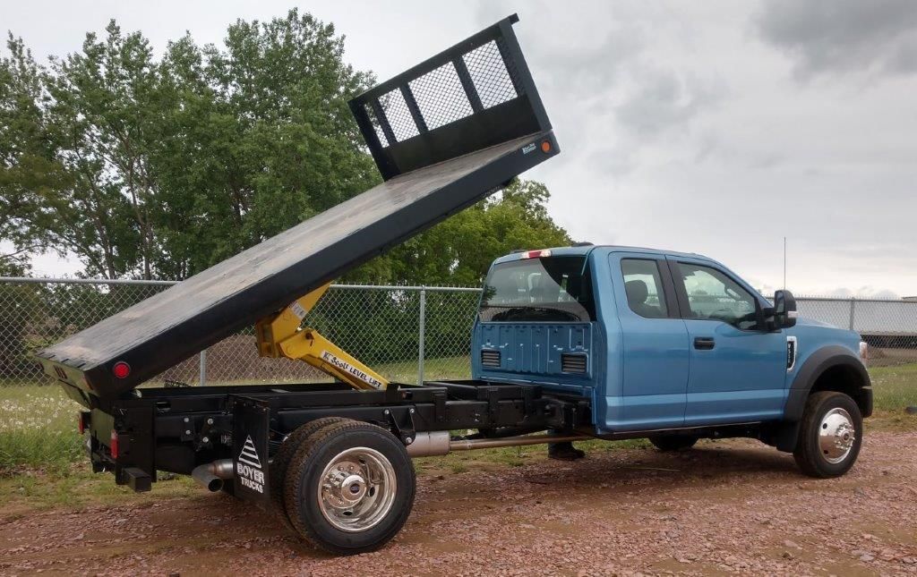 A blue dump truck is parked in a gravel lot.