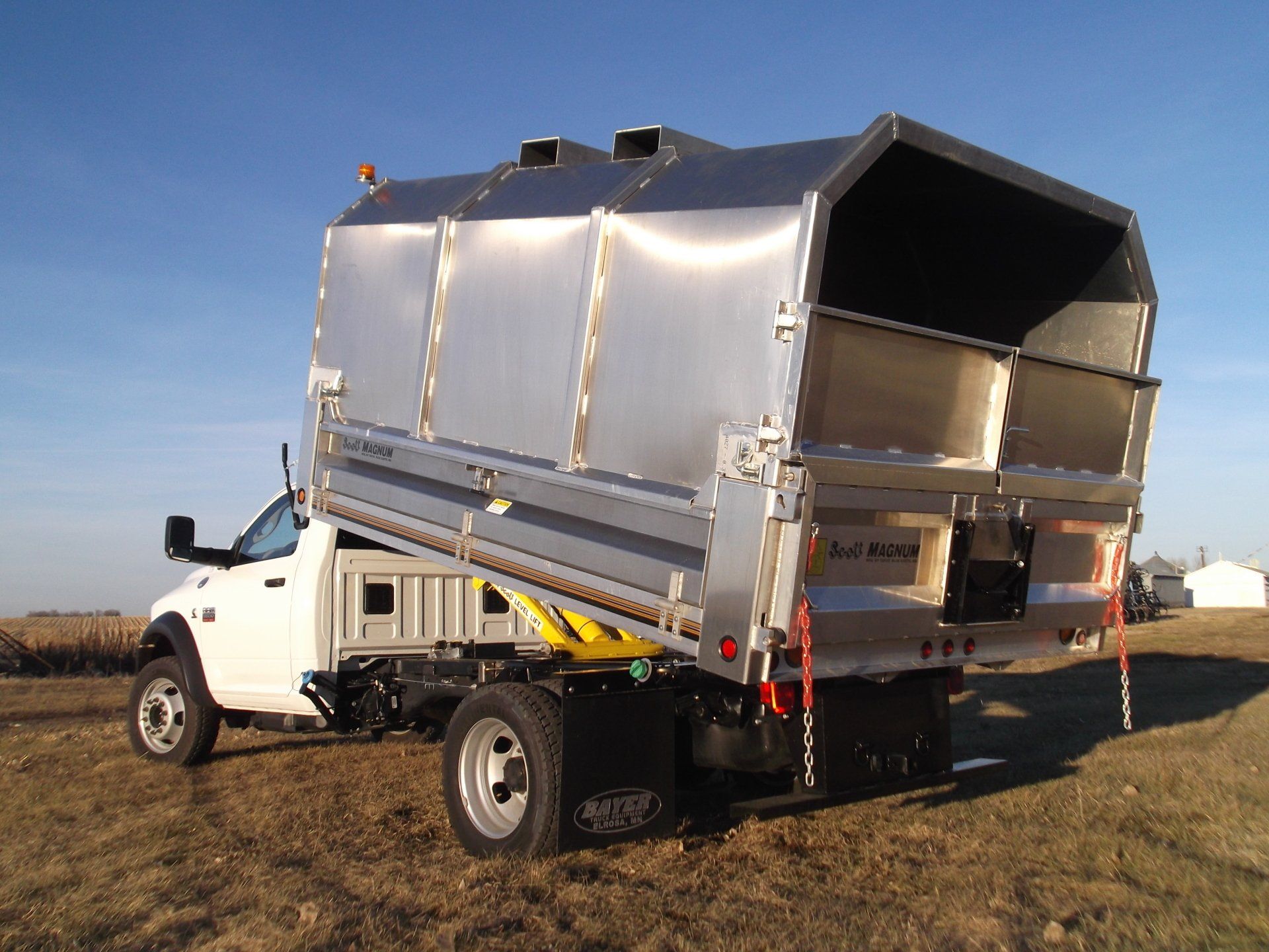 A white truck with a stainless steel roof is parked in a field