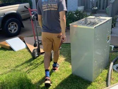 A man is walking towards a refrigerator in a yard.