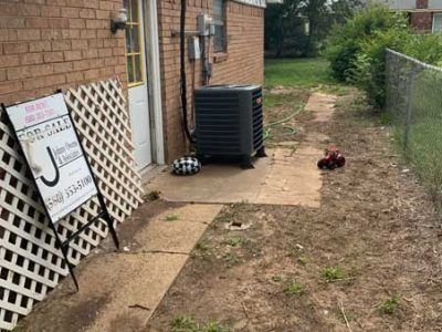 A for sale sign is sitting in front of a brick house.