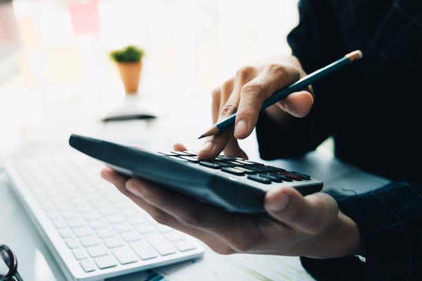 A person is using a calculator while holding a pen.