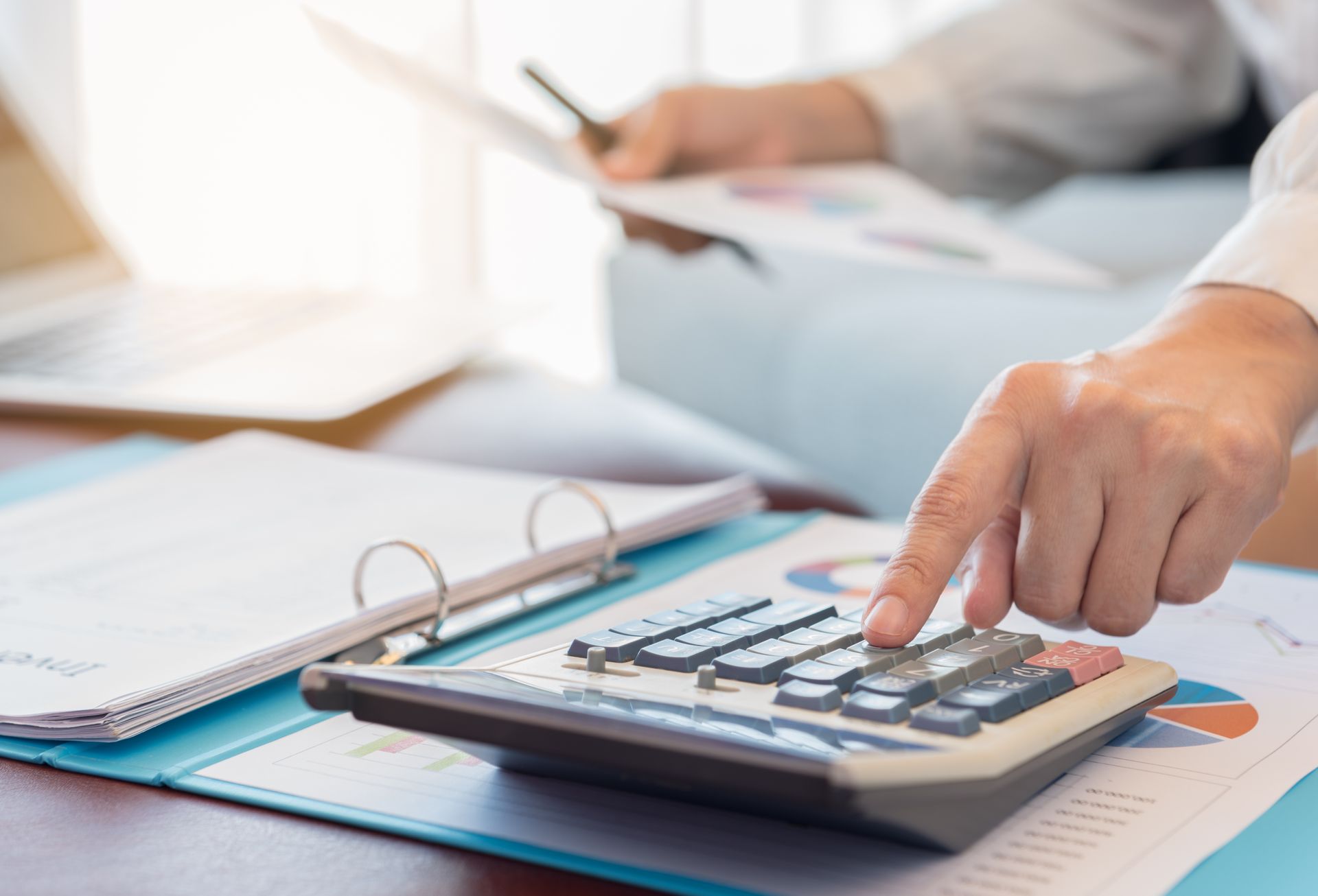 A person is using a calculator on a table.