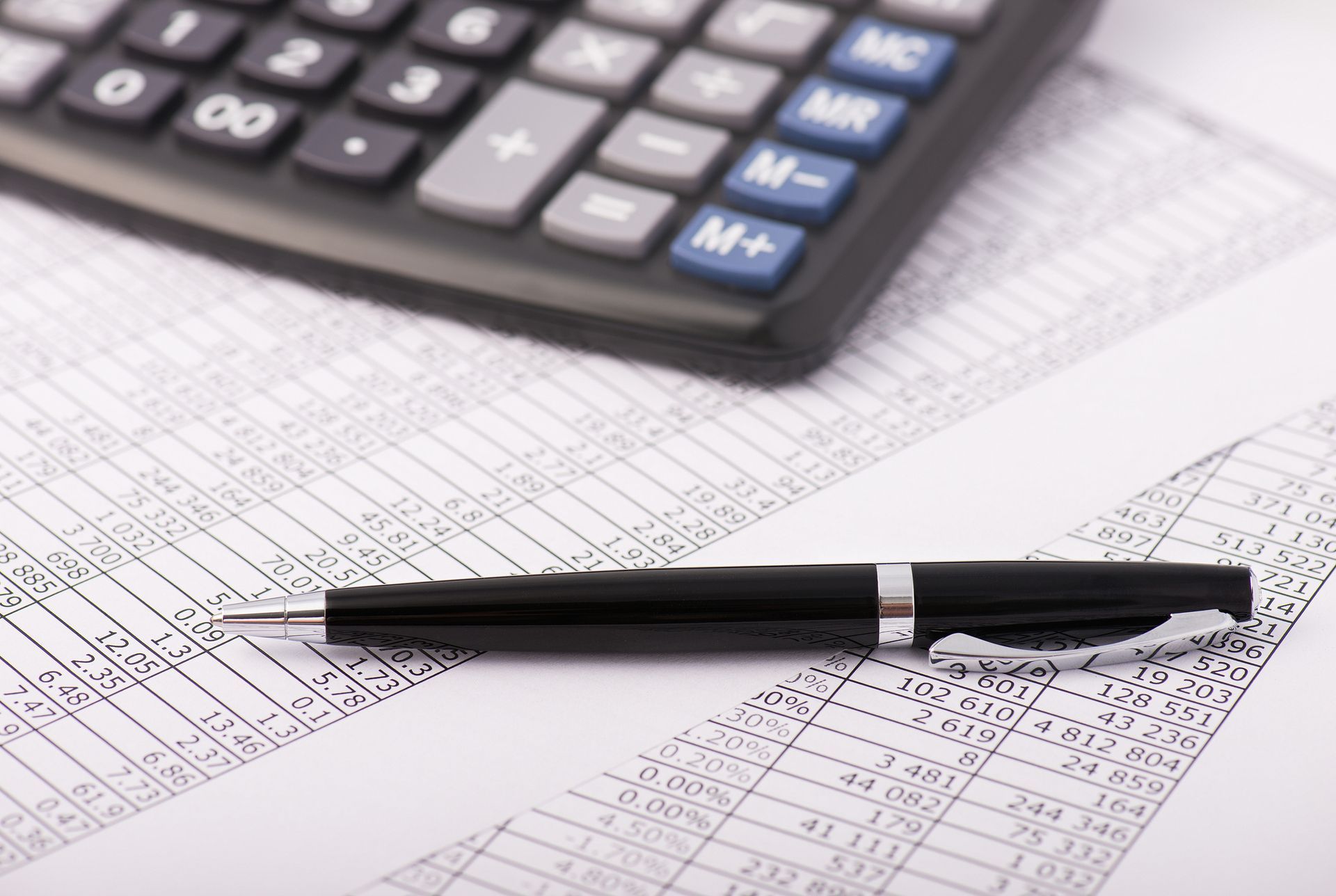 A pen is sitting on top of a piece of paper next to a calculator.