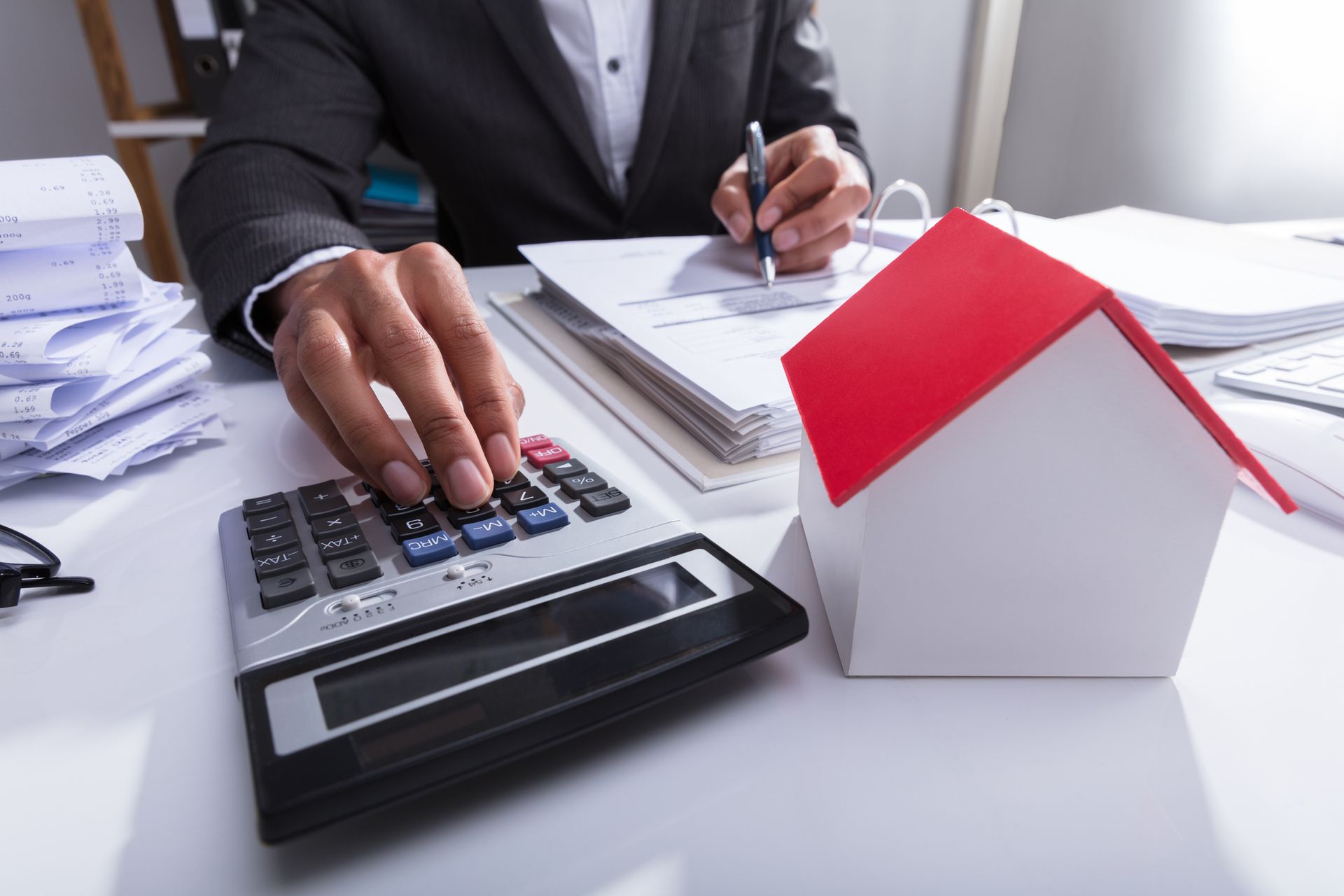 A man is using a calculator next to a model house.