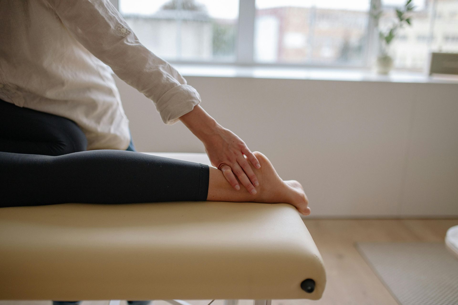 Hands massaging a foot on an examination table.