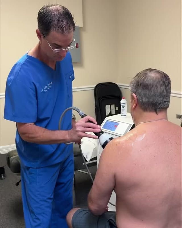 Doctor using a medical device on a patient's shoulder in a clinic.