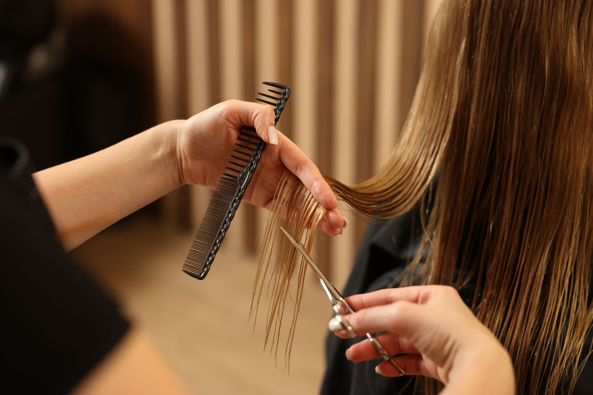 Hairdresser cutting blonde hair with scissors and comb.