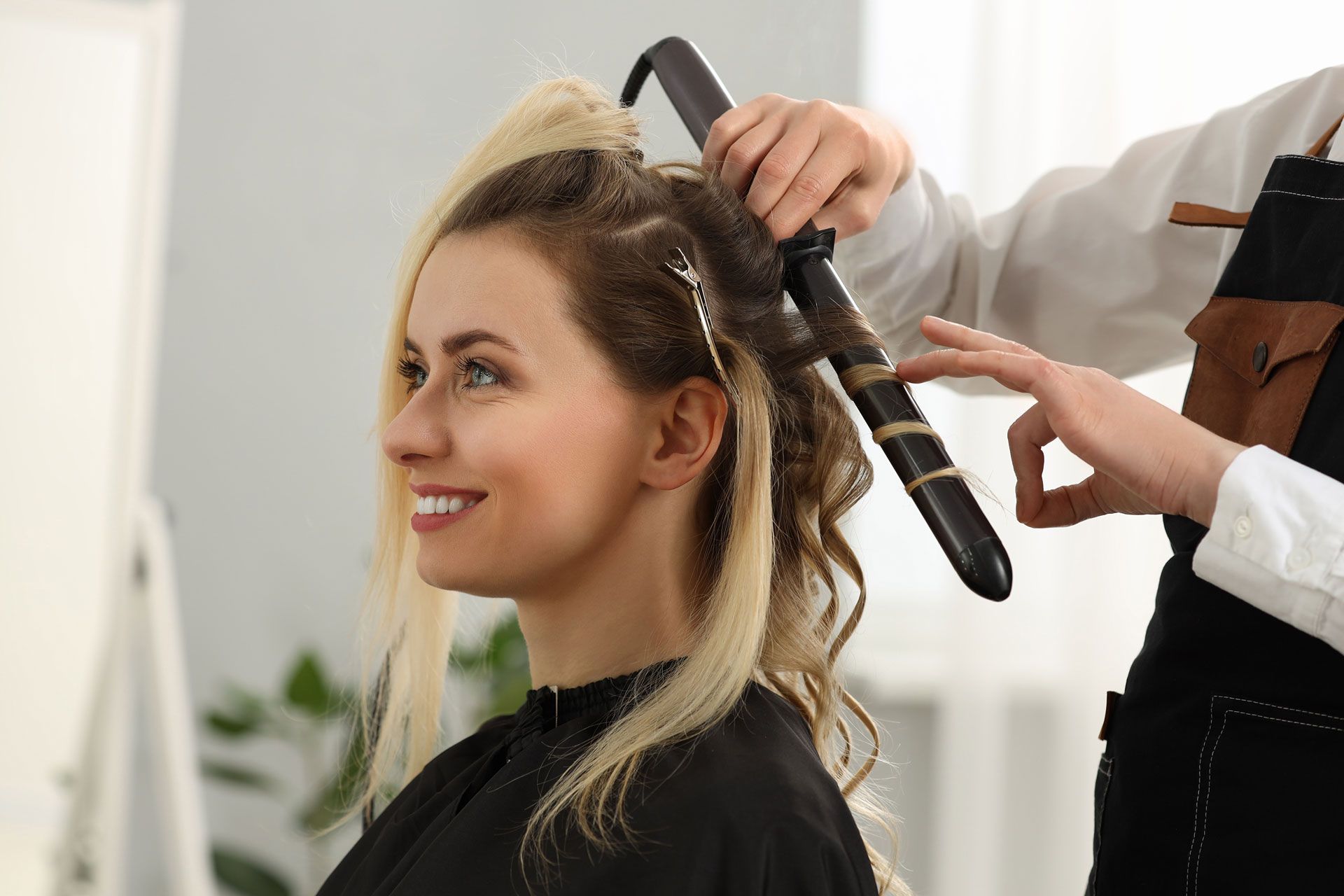 Woman getting hair curled with curling iron at salon.