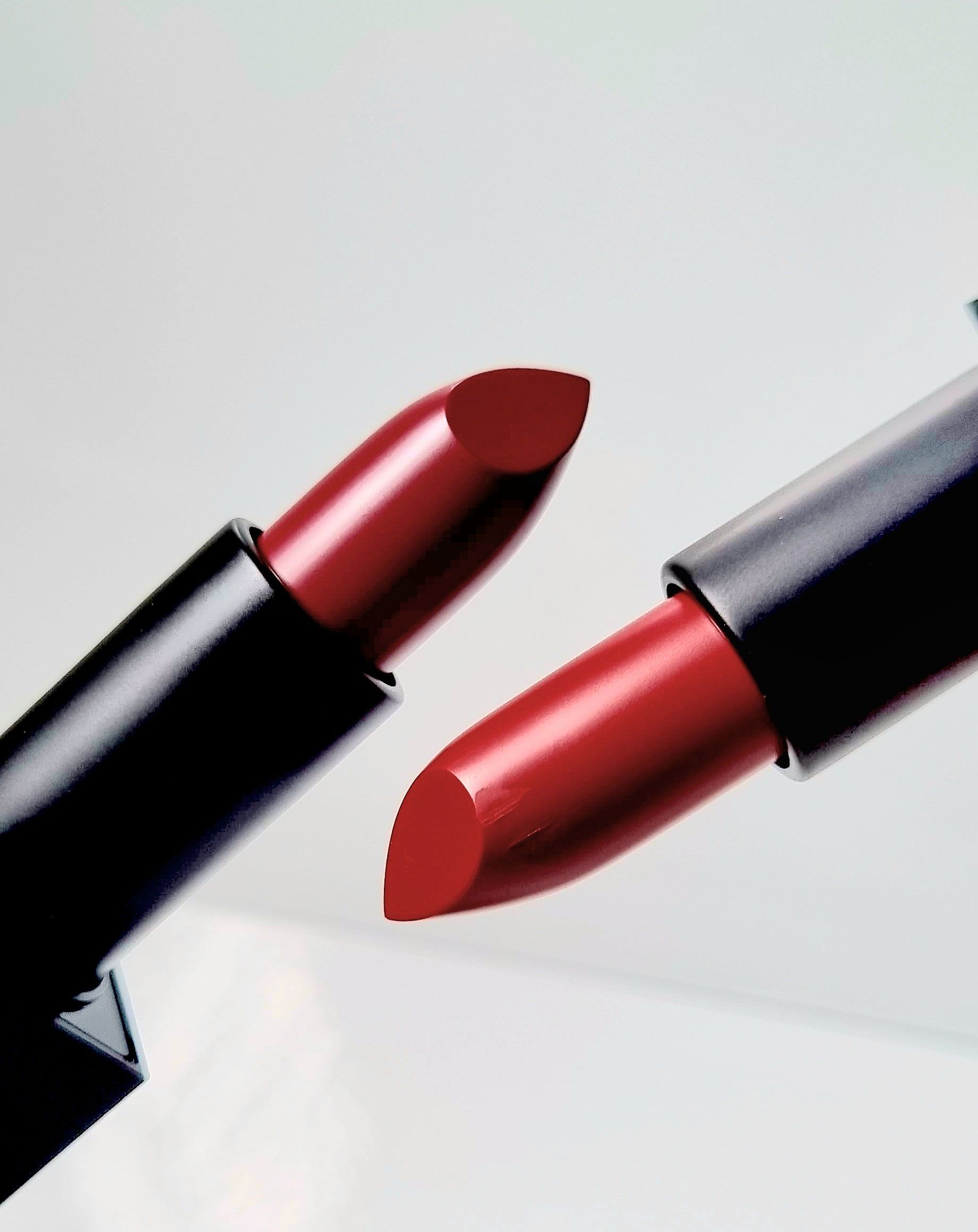Two red lipsticks with black cases, slightly angled against a white background.