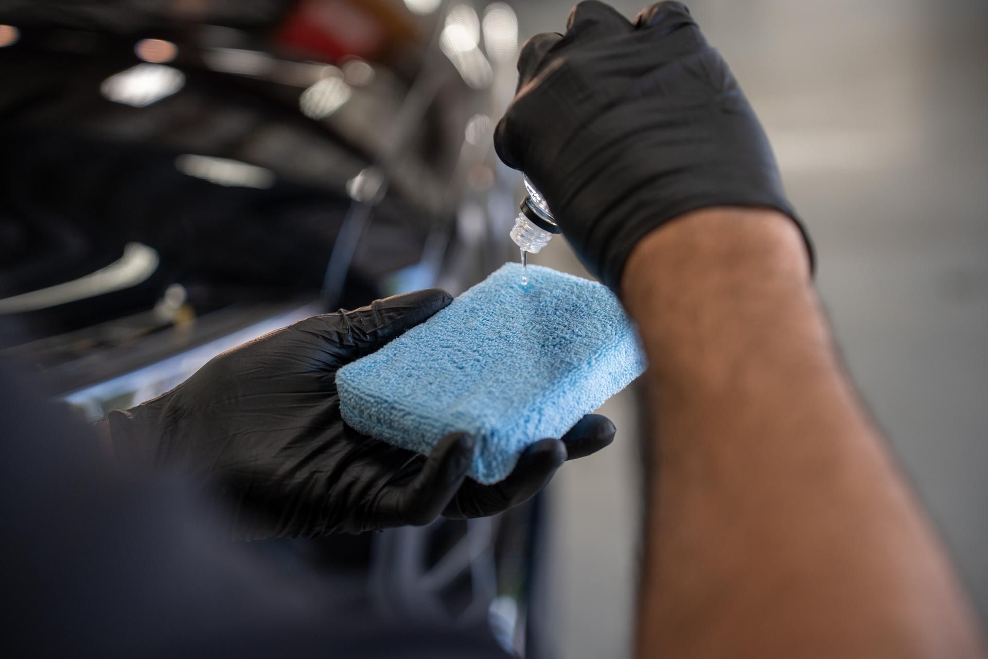 Ceramic Coating - a person wearing black gloves is holding a blue sponge