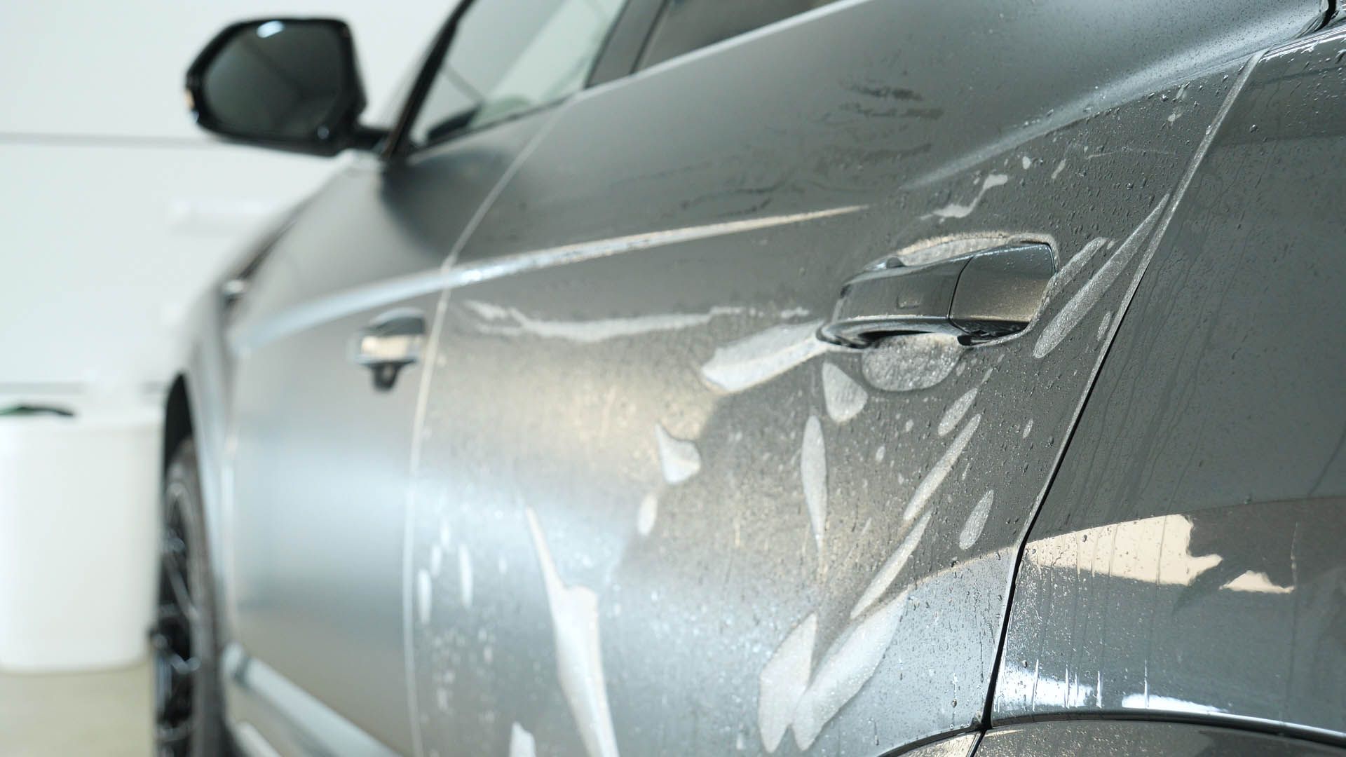 A close up of a black car with a protective film on the door.
