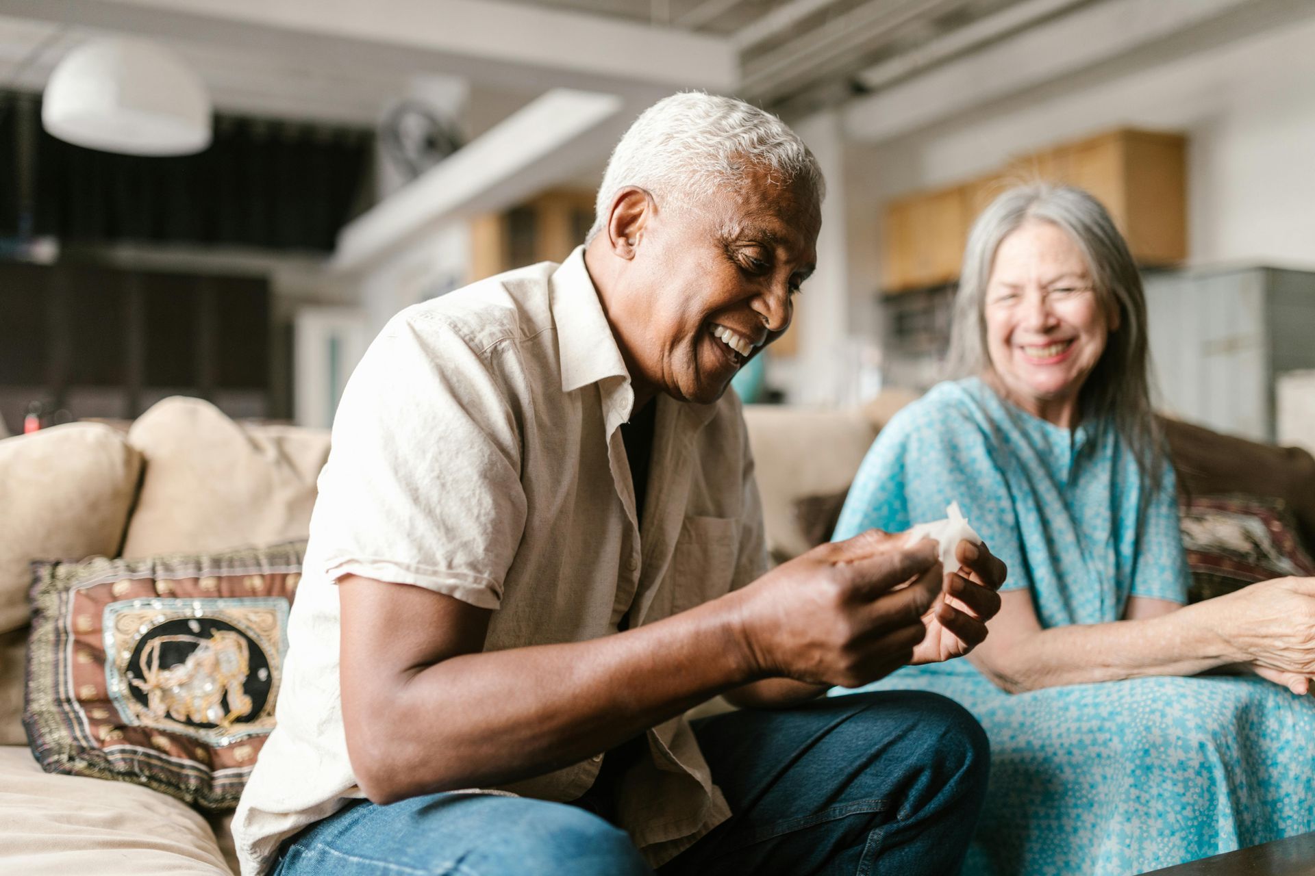 An elderly couple is sitting on a couch in a living room.