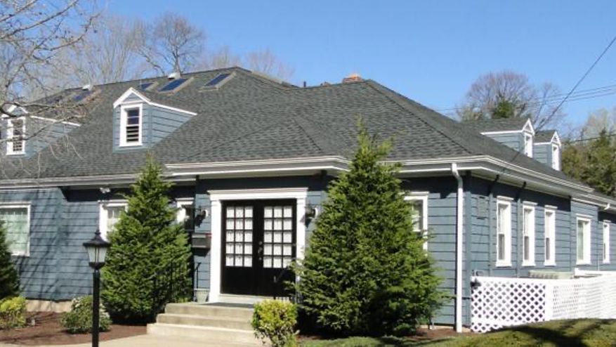 Blue house with black double doors, multiple windows, and a dark gray roof.